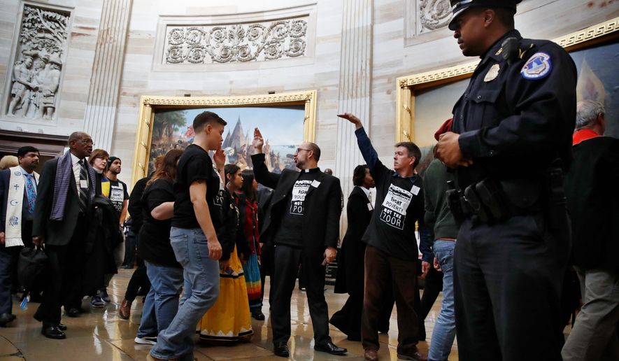 With shirts saying &quot;fight poverty not the poor,&quot; people with the &quot;Poor People&#39;s Campaign&quot; gesture the group to remain quiet as the group leaves the Capitol Rotunda after praying in an act of civil disobedience in protest of the Republican tax overhaul on Monday. (Associated Press)