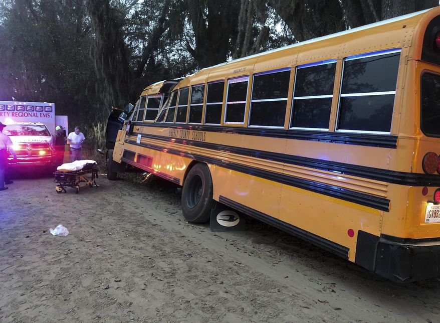 Authorities investigate the scene where a school bus crashed, Tuesday, Dec. 5, 2017, in Gum Branch, Ga. Liberty County Public Safety Director Mike Hodges said more than 20 children were riding the bus when it crashed into a tree during its morning pick-up route. (AP Photo/Lewis Levine)