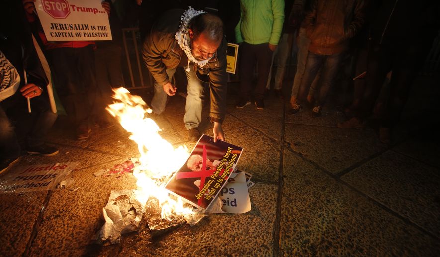 Palestinian burn a poster of the U.S. President Donald Trump during a protest in Bethlehem, West Bank, Wednesday, Dec. 6, 2017. Defying dire, worldwide warnings, President Donald Trump on Wednesday broke with decades of U.S. and international policy by recognizing Jerusalem as Israel&#x27;s capital.(AP Photo/Nasser Shiyoukhi)