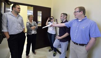 File - In this Aug. 13, 2015, file photo, David Ermold, right, as he attempts to hand Rowan County clerks Nathan Davis, left, and Roberta Earley, second from left, a copy of the ruling from U.S. District Court Judge David Bunning, instructing the county to start issuing marriage licenses, in Morehead, Ky. Ermold filed to run for county clerk on Wednesday, Dec. 6, 2017, hoping to challenge Kim Davis, who two years ago told him “God’s authority” prohibited her from complying with a U.S. Supreme Court decision that effectively legalized gay marriage nationwide. (AP Photo/Timothy D. Easley, File)