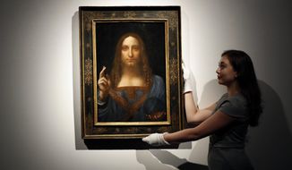 FILE- In this Oct. 24, 2017 file photo, an employee poses with Leonardo da Vinci&#39;s &amp;quot;Salvator Mundi&amp;quot; on display at Christie&#39;s auction rooms in London. The rare painting of Christ, which that sold for a record $450 million, is heading to a museum in Abu Dhabi. The newly-opened Louvre Abu Dhabi made the announcement in a tweet on Wednesday, Dec. 6. (AP Photo/Kirsty Wigglesworth, File)
