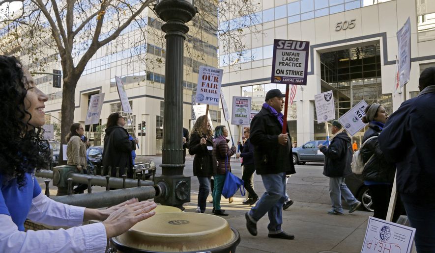 Workers picket at City Hall on Tuesday, Dec. 5, 2017, in Oakland, Calif. About 3,000 librarians, street cleaners, sewer workers, building inspectors and other city employees are striking to demand a pay raise. Oakland Mayor Libby Schaaf says the strike is unlawful because the two sides have not reached an impasse. (AP Photo/Ben Margot)