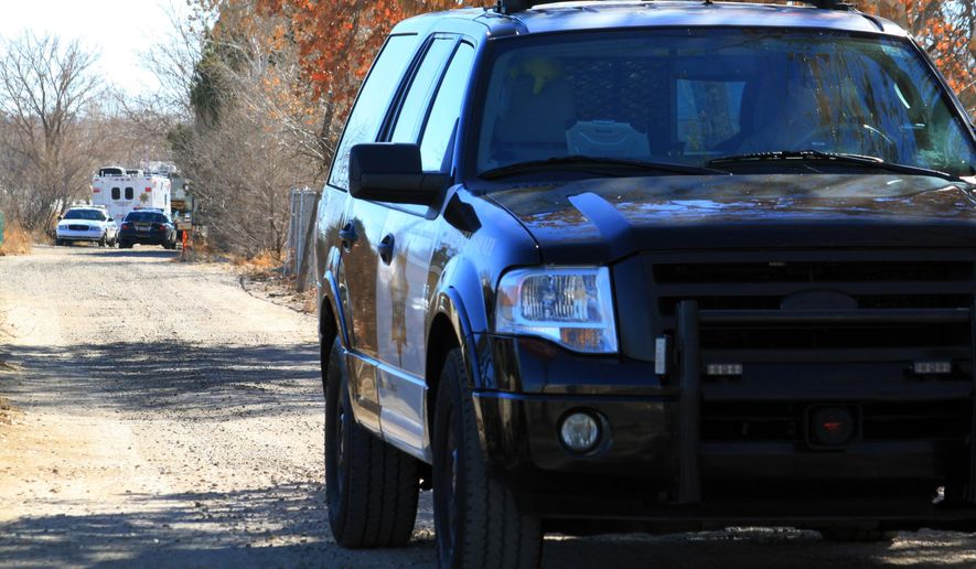 FILE - In this Jan. 20, 2013 file photo, a Bernalillo County sheriff's deputy blocks the dirt road that leads to a home where detectives were investigating the deaths of five people who were shot to death south of Albuquerque, N.M. The ACLU filed a lawsuit Tuesday, Dec. 5, 2017, in New Mexico state district court on behalf of Sherese Crawford, 38, against the Bernalillo County Sheriff's Department stemming from three traffic stops that the ACLU said amounted to racial profiling. (AP Photo/Susan Montoya Bryan, file)