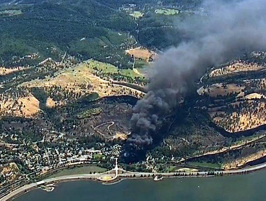 FILE- In this June 3, 2016, file image, from video provided by KGW-TV, smoke billows from a Union Pacific train that derailed near Mosier, Ore., in the scenic Columbia River Gorge. The Trump administration is angering environmental groups and residents of the Columbia River Gorge by rolling back a 2015 rule on oil train safety. (KGW-TV via AP, File)