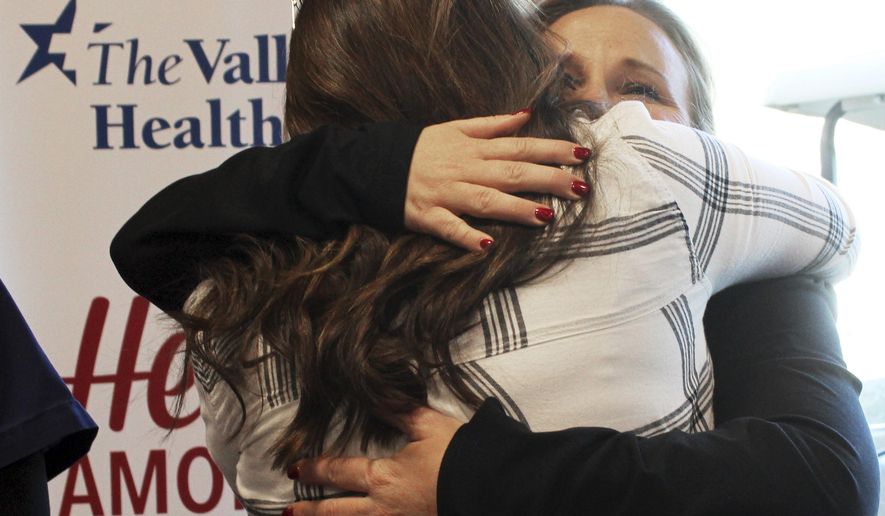 Nurse Sydney Patton, facing camera, hugs a survivor of the Oct. 1, 2017 mass shooting at a gathering at Spring Valley Hospital in Las Vegas Friday, Dec. 8, 2017. Survivors handed thank-you baskets to nurses and others at the emergency room of Spring Valley Hospital, which helped more than 50 patients after the shooting. (AP Photo/Regina Garcia Cano)