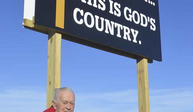 ADVANCE FOR USE SUNDAY, DEC. 10 - In this Nov. 27, 2017 photo, former state Sen. Richard Peterson poses by a religious sign in Norfolk, Neb. Peterson is paying to create and erect several small billboards that remind drivers around Norfolk that God is always available to listen. ( Jerry Guenther/The Norfolk Daily News via AP)