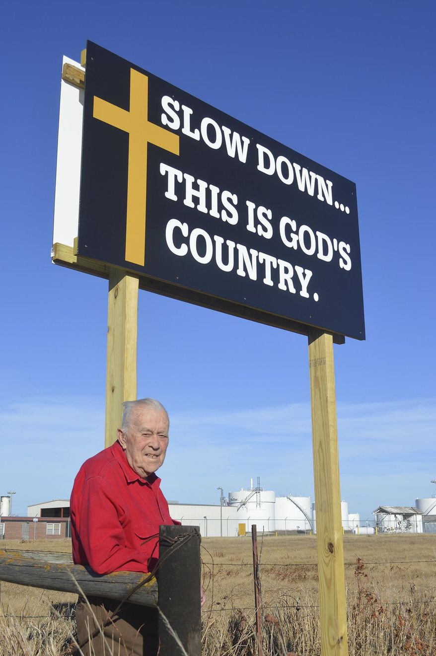 ADVANCE FOR USE SUNDAY, DEC. 10 - In this Nov. 27, 2017 photo, former state Sen. Richard Peterson poses by a religious sign in Norfolk, Neb. Peterson is paying to create and erect several small billboards that remind drivers around Norfolk that God is always available to listen. ( Jerry Guenther/The Norfolk Daily News via AP)