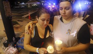 FILE - In this June 12, 2016, file photo, Sonia Parra, left, and Andrea Parra, who said they lost friends in the Pulse nightclub shooting, hold candles on the street corner near the nightclub in Orlando, Fla. In the five years since a gunman killed 20 children and six adults at the Sandy Hook elementary school in Newtown, Conn., the nation has seen a number of massacres topping the death toll from that shooting. (Curtis Compton/Atlanta Journal-Constitution via AP, File)