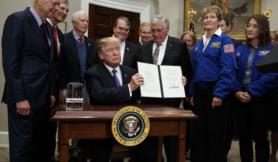 President Donald Trump holds up a policy directive to send American astronauts back to the moon, and eventually Mars, in the Roosevelt Room of the White House, Monday, Dec. 11, 2017, in Washington. (AP Photo/Evan Vucci)