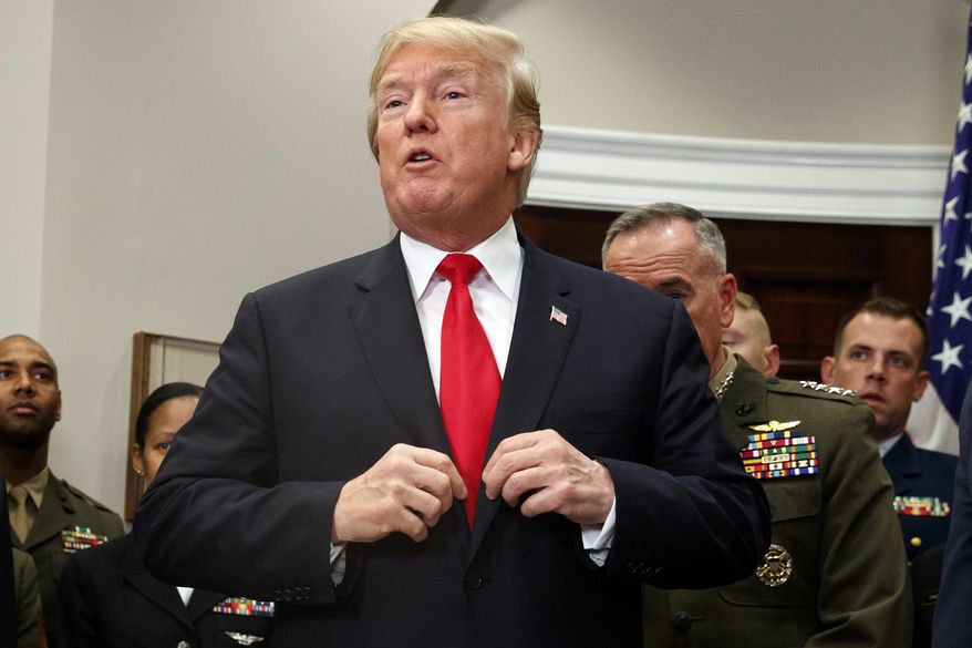 President Donald Trump adjusts his jacket after signing the National Defense Authorization Act for Fiscal Year 2018 bill, in the Roosevelt Room of the White House, Tuesday, Dec. 12, 2017, in Washington. (AP Photo/Evan Vucci)