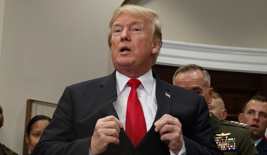 President Donald Trump adjusts his suit jacket after signing the National Defense Authorization Act for Fiscal Year 2018 bill, in the Roosevelt Room of the White House, Tuesday, Dec. 12, 2017, in Washington. (AP Photo/Evan Vucci)