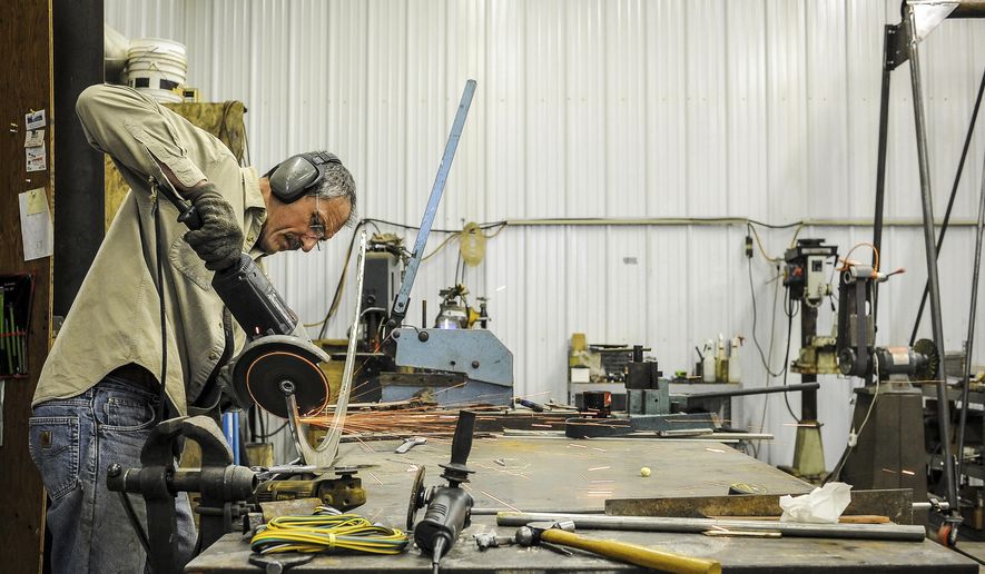 In this Dec. 1, 2017 photo, Sebastien Richer, a master metalsmith, works on a coffee table in his shop in Dodge Center, Minn. His artistry is in his ability to mold and shape metal in any way he wants. (Joe Ahlquist/The Rochester Post-Bulletin via AP)