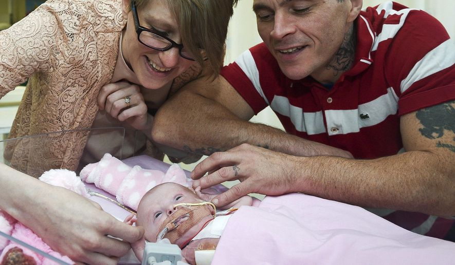 Naomi Findlay and Dean Wilkins, look at their daughter, three-week-old Vanellope Hope Wilkins who was born with an extremely rare condition in which the heart grows on the outside of the body, at Glenfield Hospital in Leicester, Monday Dec. 11, 2017. (Ben Birchall/PA via AP)