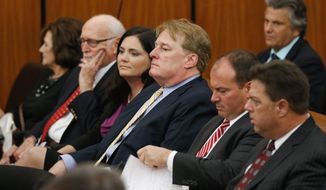 FILE - In an Oct. 24, 2017 file photo, South Carolina Rep Rick Quinn, center, sits with his wife, Amy McRae Benck, his parents, Richard Quinn, Sr. and Ruth LeJeune Quinn, left, and Matthew Richardson and Tracy Edge, right, during bond court in Columbia, S.C. Quinn is resigning Wednesday, Dec. 13, 2017, an hour before a hearing in a Statehouse corruption probe that has ensnared him along with several other lawmakers.  (Tracy Glantz/The State via AP, File)