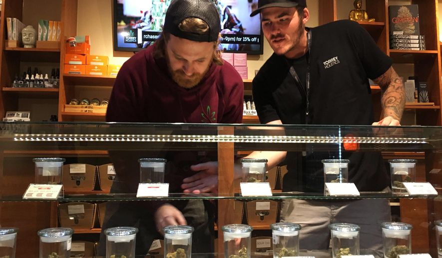 Torrey Holistics employees, Matt Sullivan, left, and Taron McElroy, arrange jars of cannabis in San Diego, Calif., Thursday, Dec. 14, 2017. On Thursday, California issued its first batch of business licenses for the state's upcoming legal marijuana market, setting the stage for sales to begin to adults in January. The first license for recreational retail sales went to Torrey Holistics in San Diego. (AP Photo/Julie Watson)