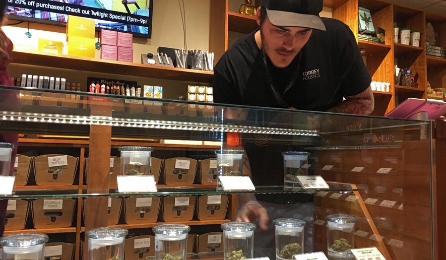 Torrey Holistics employee Taron McElroy arranges jars of cannabis in San Diego, Calif., Thursday, Dec. 14, 2017. On Thursday, California issued its first batch of business licenses for the state's upcoming legal marijuana market, setting the stage for sales to begin to adults in January. The first license for recreational retail sales went to Torrey Holistics in San Diego. (AP Photo/Julie Watson)