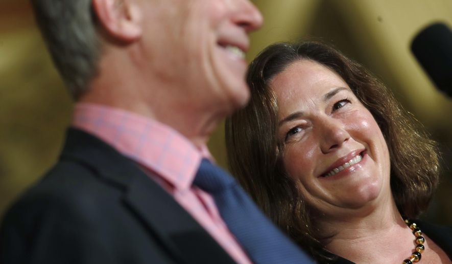 Melissa Hart, back, a University of Colorado law professor, smiles as she is introduced by Colorado Gov. John Hickenlooper as the newest member of the Colorado Supreme Court Wednesday, Dec. 14, 2017, during a news conference in the State Capitol in Denver. Hart will take the place of Allison Eid, who was appointed to Denver's federal appeals court, on the state's seven-member Supreme Court. (AP Photo/David Zalubowski)