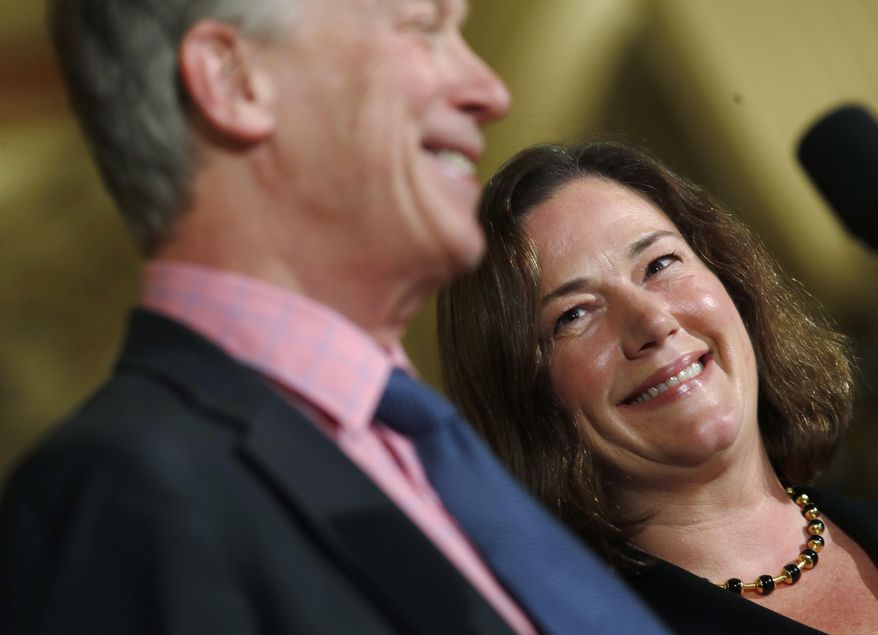 Melissa Hart, back, a University of Colorado law professor, smiles as she is introduced by Colorado Gov. John Hickenlooper as the newest member of the Colorado Supreme Court Wednesday, Dec. 14, 2017, during a news conference in the State Capitol in Denver. Hart will take the place of Allison Eid, who was appointed to Denver's federal appeals court, on the state's seven-member Supreme Court. (AP Photo/David Zalubowski)