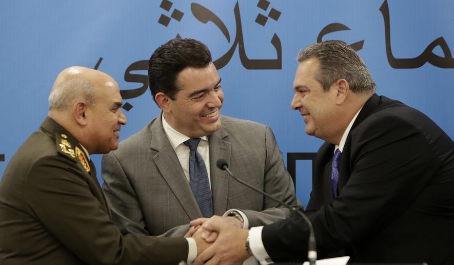 Cyprus' Defense Minister Christoforos Fokaides, center, shakes hands with his Greek counterpart Panos Kammenos, right, and Egyptian Defense Minister Sedki Sobhi after their first of three-way talks at the "Zenon" Search and Rescue Coordination Center next to Cyprus' Larnaca international airport, on Thursday, Dec. 14, 2017. The defense ministers of Cyprus, Egypt and Greece have agreed to step up cooperation in combatting drug, weapons and people trafficking in the east Mediterranean and to share information on countering the threat of terrorism. (AP Photo/Petros Karadjias)