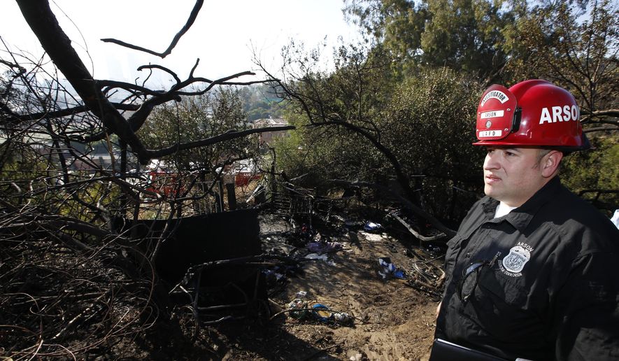 Los Angeles Fire Department Fire Arson Counter-Terrorism investigator Angel Alvarez checks a burned out homeless camp after a brush fire erupted in hills in Elysian Park in Los Angeles Thursday, Dec. 14, 2017. The National Weather Service said extreme fire danger conditions could last through the weekend due to lack of moisture along with a likely increase in wind speeds. (AP Photo/Damian Dovarganes)