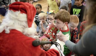 Luke Holley, 4, receives his gift from Santa Claus at the Savannah Elks Lodge #183 Christmas gathering Sunday, Dec. 17, 2017, in Savannah, Ga. The Elks Lodge invited 175 children and their families from Hunter Army Airfield, Fort Stewart, Safe Shelter, Salvation Army and the local Aidmore Foster Home program out to their Southside lodge to celebrate the season. (Will Peebles/Savannah Morning News via AP)
