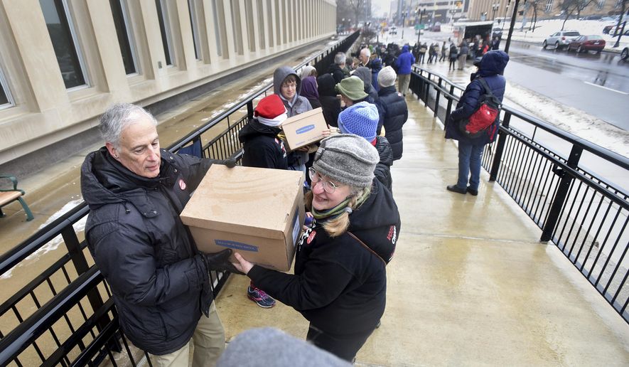 Jim Nelson of DeWitt, left, and Carolyn Hejkil of Scio Twp. Mich., team up to deliver petitions to change the way districts are created in Michigan arrive Monday, Dec 18, 2017, at the Secretary of State's office in Lansing. Mich., with over 400,000 signatures on them. Volunteers formed a human chain and handed the boxes from the truck, up the stairs and to the office. (Dale G Young/Detroit News via AP)