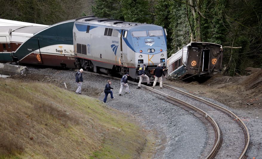 Police officials walk over tracks near a curve at the back of where an Amtrak train derailed above Interstate 5, Monday, Dec. 18, 2017, in DuPont, Wash. (AP Photo/Elaine Thompson)