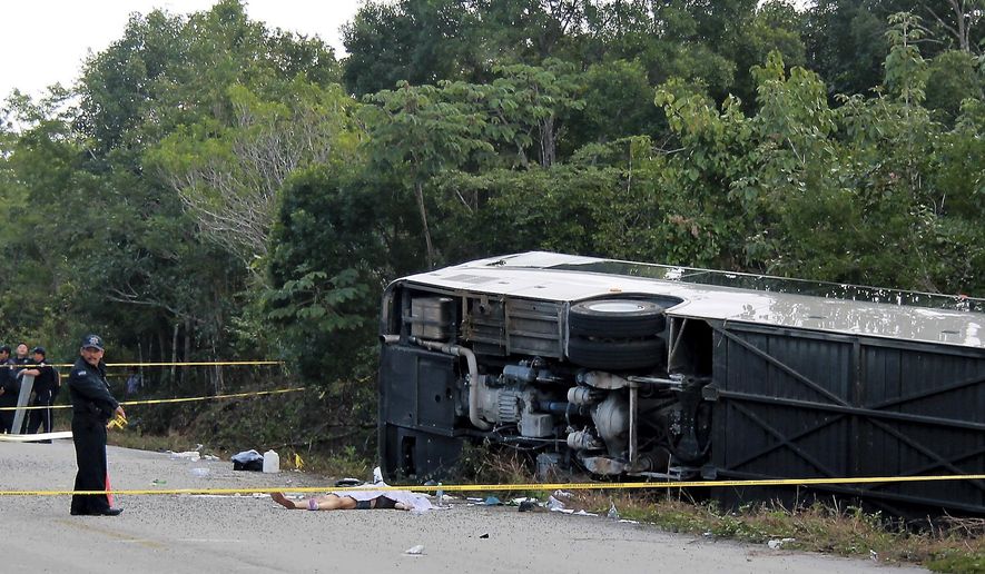 The lifeless body of a passenger lies next to an overturned bus in Mahahual, Quintana Roo state, Mexico, Tuesday, Dec. 19, 2017. The bus carrying cruise ship passengers to the Mayan ruins at Chacchoben in eastern Mexico flipped over on the highway early Tuesday. (Novedades de Quintana Roo via AP)