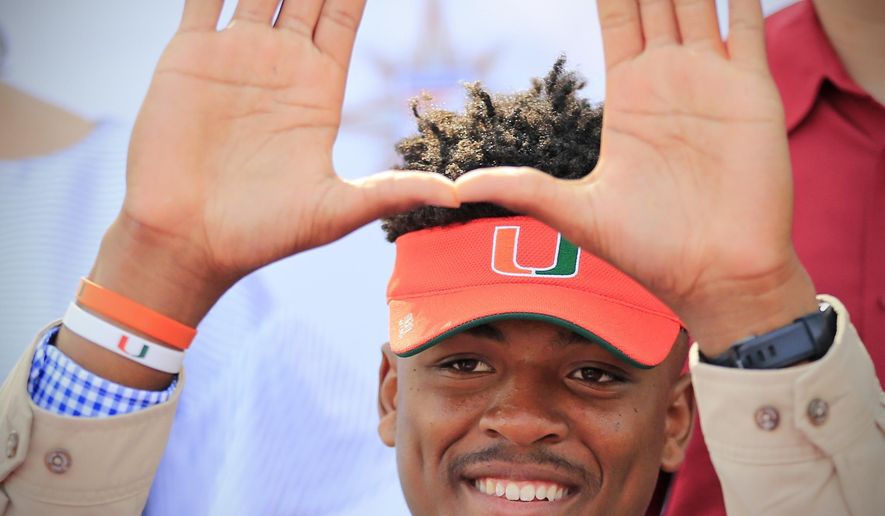Gregory Rousseau, a Champagnat Catholic High School football player, makes a "U" gesture announcing his intentions to attend the University of Miami during the NCAA college football early signing period, Wednesday, Dec. 20, 2017, in Sunrise, Fla. (Al Diaz/Miami Herald via AP)