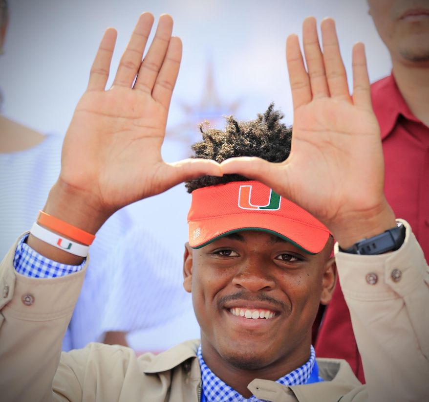 Gregory Rousseau, a Champagnat Catholic High School football player, makes a "U" gesture announcing his intentions to attend the University of Miami during the NCAA college football early signing period, Wednesday, Dec. 20, 2017, in Sunrise, Fla. (Al Diaz/Miami Herald via AP)