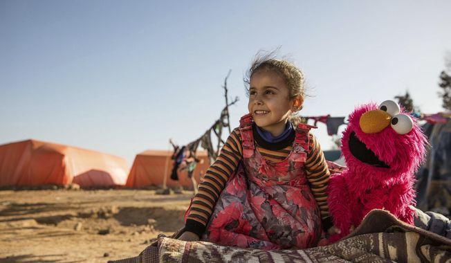 In this Feb. 2017 photo Photo courtesy of Ryan Heffernan and Sesame Workshop, a young girl engages with Sesame Street caricature Elmo at an informal tented settlement near Mafraq,Jordan. The John D. and Catherine T. MacArthur Foundation announced Wednesday, Dec. 20, 2017, that Sesame Workshop and International Rescue Committee will get a $100 million grant from a Chicago-based foundation. for a joint program that will include home visits focused on early learning, child development centers and a local version of "Sesame Street." (Ryan Heffernan/Sesame Workshop via AP)