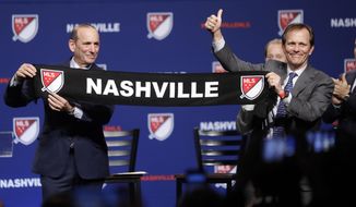 Major League Soccer commissioner Don Garber, left, presents a scarf to John Ingram, chairman of Ingram Industries Inc., as Garber announces that Nashville, Tenn. has been awarded a Major League Soccer franchise Wednesday, Dec. 20, 2017, in Nashville, Tenn. Ingram is the head of the group seeking to bring the team to Nashville. (AP Photo/Mark Humphrey)