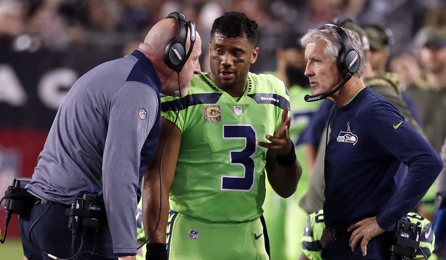 FILE - In this Thursday, Nov. 9, 2017, file photo, Seattle Seahawks quarterback Russell Wilson (3) speaks with head coach Pete Carroll, right, and assistant head coach Tom Cable during an NFL football game against the Arizona Cardinals in Glendale, Ariz. The Seahawks have been fined $100,000 for not properly following concussion protocol with Wilson during this game in November. The NFL and NFLPA announced their decision Thursday, Dec. 21, 2017, following an investigation that lasted more than a month.. (AP Photo/Rick Scuteri, File)