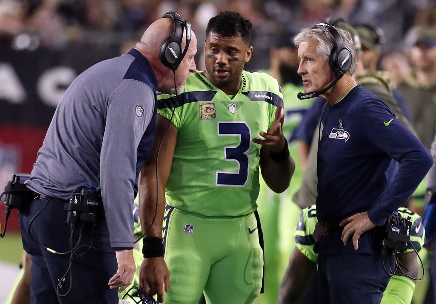 FILE - In this Thursday, Nov. 9, 2017, file photo, Seattle Seahawks quarterback Russell Wilson (3) speaks with head coach Pete Carroll, right, and assistant head coach Tom Cable during an NFL football game against the Arizona Cardinals in Glendale, Ariz. The Seahawks have been fined $100,000 for not properly following concussion protocol with Wilson during this game in November. The NFL and NFLPA announced their decision Thursday, Dec. 21, 2017, following an investigation that lasted more than a month.. (AP Photo/Rick Scuteri, File)