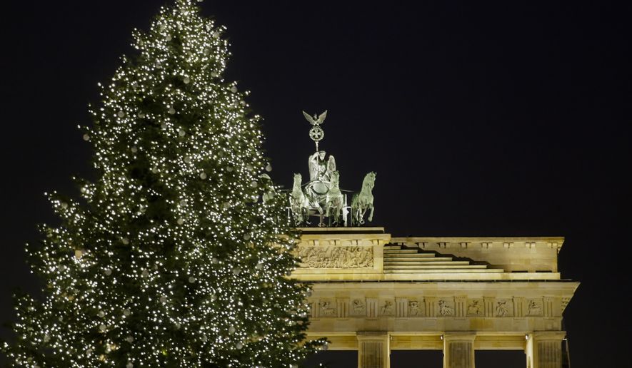 A Christmas tree is illuminated in front of Germany's landmark Brandenburg Gate a day before Christmas Eve in Berlin, Saturday, Dec. 23, 2017. (AP Photo/Markus Schreiber) **FILE**