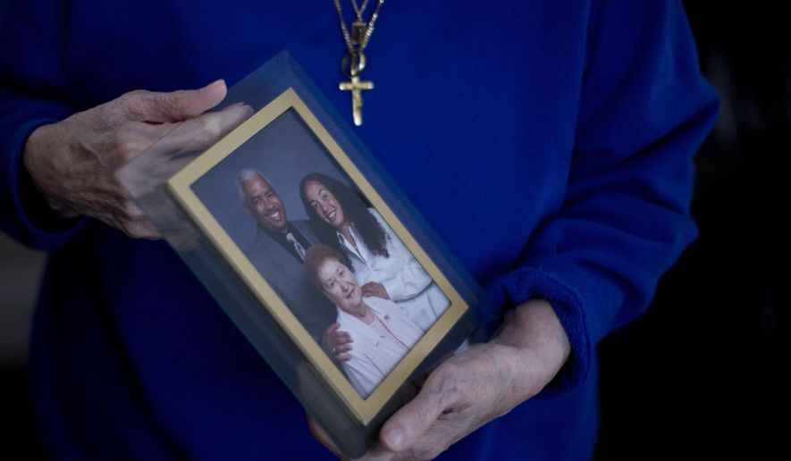 In this Jan. 11, 2017, photo, a person holds a photo of Karen Batts, pictured at right, in Oregon. Batts died of hypothermia in a parking garage in Portland, Ore. (Beth Nakamura/The Oregonian via AP)