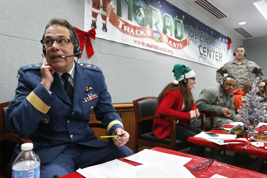 FILE - In this Dec. 24, 2014, file photo, Canadian Brig. Gen. Guy Hamel, NORAD and USNORTHCOM Deputy Director of Policy, Strategy, and Plans, joins other volunteers taking phone calls from children around the world asking where Santa is and when he will deliver presents to their homes, inside a phone-in center during the annual NORAD Tracks Santa Operation, at the North American Aerospace Defense Command, at Peterson Air Force Base, Colo. Hundreds of military and civilian volunteers at NORAD are estimated to field more than 100,000 calls this year throughout Christmas Eve, from children from all over the world eager to hear about Santa's progress. (AP Photo/Brennan Linsley, file)