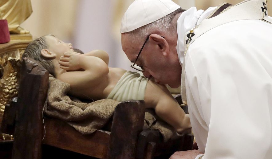 Pope Francis kisses a statue of Baby Jesus as he celebrates the Christmas Eve Mass in St. Peter's Basilica at the Vatican, Sunday, Dec. 24, 2017. (AP Photo/Alessandra Tarantino)