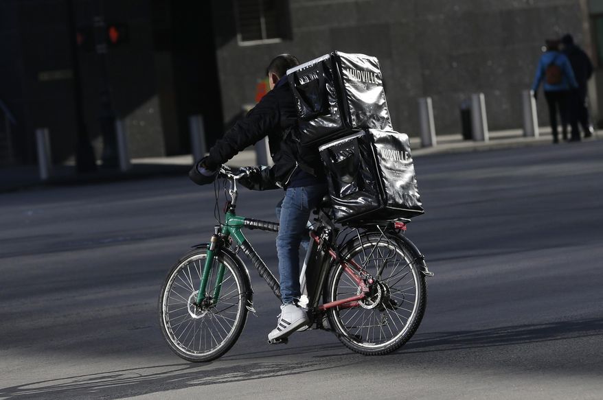 In this Thursday, Dec. 21, 2017 photo, a man making deliveries rides an electronic bike in New York. A plan to intensify a crackdown on electric bicycles is causing concern among the New York City’s largely immigrant delivery workforce.  (AP Photo/Seth Wenig)
