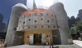 FILE- In this Aug. 10, 2017 file photo, a construction worker walks in front of the St. Nicholas National Shrine in New York. Work on the Greek Orthodox church destroyed in the Sept. 11 attacks next to the World Trade Center memorial plaza has been temporarily suspended by the construction company.  It comes amid financial difficulties and questions over how funds have been managed. (AP Photo/Mark Lennihan, File)