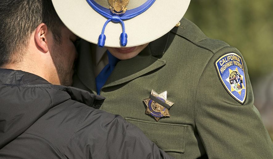 A black band covers the badge of California Highway Patrol Officer Jonathan Velazquez as he is comforted following a bell ringing ceremony held for CHP Officer Andrew Camilleri Sr., at the highway patrol academy Wednesday, Dec. 27, 2017, in West Sacramento, Calif. Camilleri Sr, was sitting into the passenger seat of the patrol vehicle operated by Velazquez, that was parked on the shoulder of Interstate 880 Christmas Eve night when their vehicle was struck by vehicle that drifted off the highway. Camilleri was killed and Velazquez, who suffered miner injuries, was treated and released from a nearby medical center. The driver of the other vehicle, who was believed to be under influence of marijuana and alcohol at the time of the accident, remains in the hospital with serious injuries. (AP Photo/Rich Pedroncelli)
