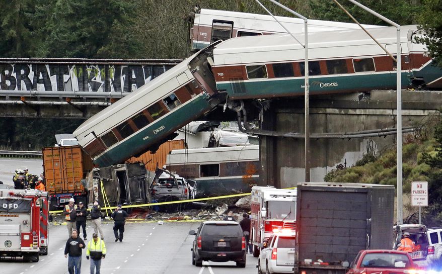 FILE - In this Dec. 18, 2017 file photo, cars from an Amtrak train lay spilled onto Interstate 5 below alongside smashed vehicles as some train cars remain on the tracks above in DuPont, Wash. Dozens of 911 call recordings released by South Sound 911 Dispatch provide a vivid account of the Dec. 18 wreck from survivors and witnesses. Authorities say it could take more than a year to understand how the train carrying 85 passengers and crew members could have ended in disaster as it made its inaugural run along a fast, new 15-mile (24-kilometer) bypass route. (AP Photo/Elaine Thompson, file)
