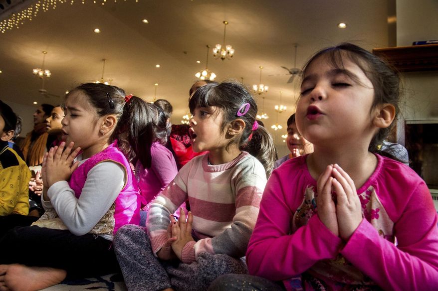 In this Nov. 19, 2017 photo, from left, Sowmya Anand, Mishika Mukhopadyay, and Amili Sinha, join other children as they sing bhajans, which are songs of praise of God, as the faithful gather at the Hindu Temple of Central Illinois, which is a destination for Hindu families across the region in West Peoria, Ill. Sitting on 25 acres atop a high bluff near Farmington Road, the Temple space presents multiple Deities,which the faithful use to help focus their meditation on the Almighty. (Fred Zwicky/Journal Star via AP)