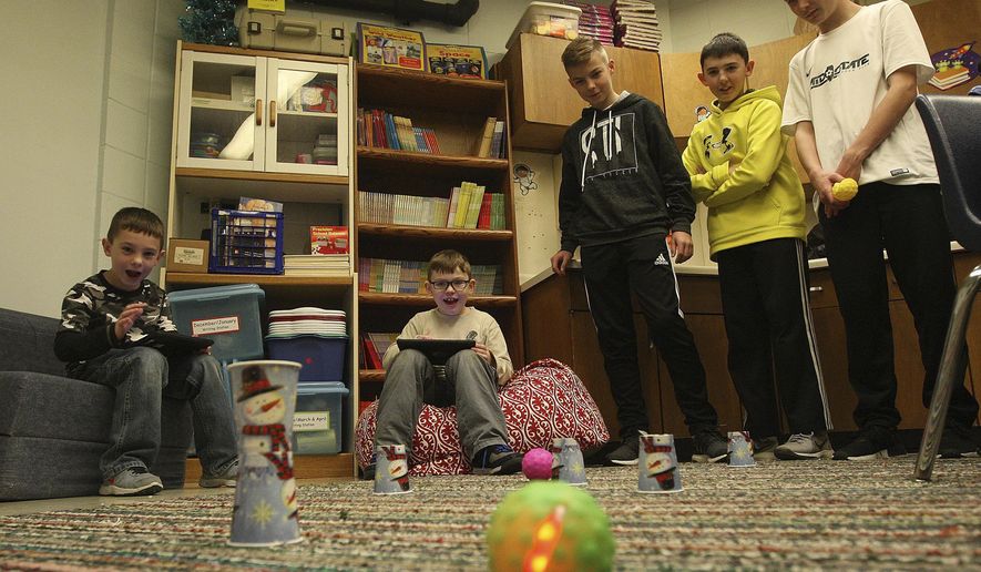 In this Dec. 18, 2017 photo, from left, second graders Urijah Burns and Eli Binkley play a remote controlled game with help from eighth graders Christian Schanefelt, Joey Young and Austin Cohn from Warrensburg-Latham Middle School at the elementary School in Warrensburg, Ill. The Middle School students at Latham spend time playing games with elementary school students for their kindness project. Junior high teacher Crystal Hoadley, who teaches science to sixth, seventh and eighth grade students, has been overseeing The Kindess Project for a few years now. (Jim Bowling/Herald & Review via AP)/Herald & Review via AP)