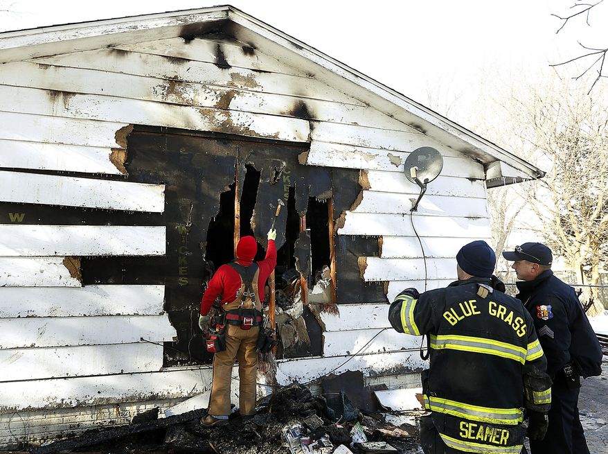 Blue Grass Fire Chief Brian Seamer and Blue Grass Police Sgt. Garrett Jahns watch a home being secured on East Salem Street where 4 people died in a fire in Blue Grass, Iowa Monday Dec. 25, 2017. Jahns said Tuesday that he couldn't release any of the victims' names or ages yet but that the four were related. (Jeff Cook/Quad City Times via AP)