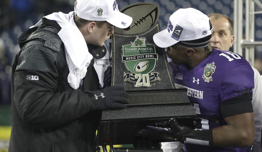 Northwestern quarterback Clayton Thorson, left, and safety Godwin Igwebuike (16) kiss the trophy after Northwestern beat Kentucky 24-23 in the Music City Bowl NCAA college football game Friday, Dec. 29, 2017, in Nashville, Tenn. Thorson was injured during the game. (AP Photo/Mark Humphrey)