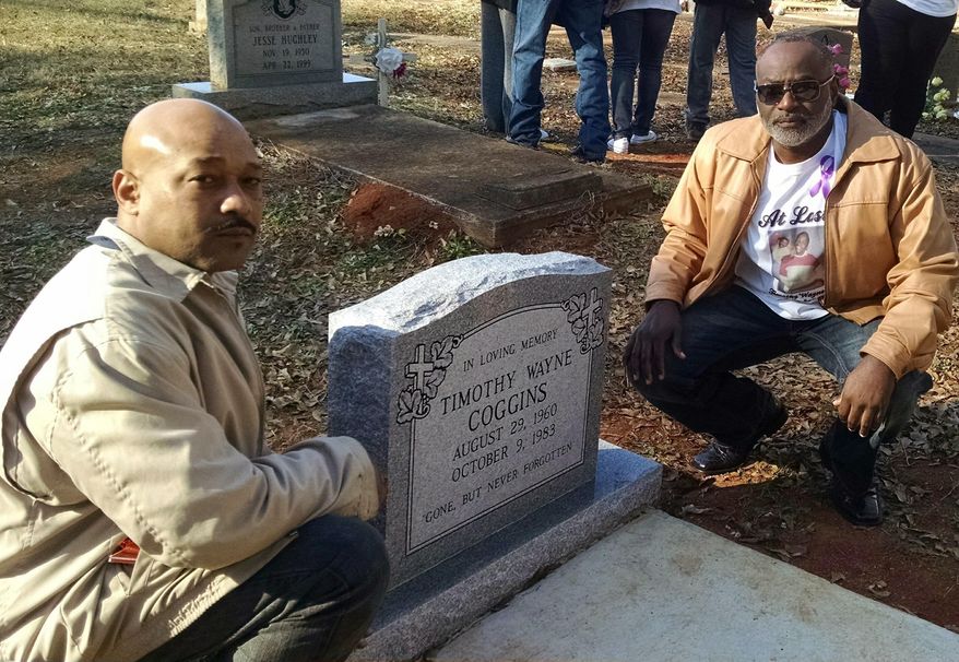 Ramon, left, and Tyrone Coggins, brothers of Timothy Wayne Coggins, pose beside the new headstone on Timothy Coggins' grave in Zebulon, Ga. Saturday, Dec. 30, 2017. Timothy Wayne Coggins was killed in 1983. His slaying remained unsolved for decades. In October 2017, authorities charged two men with killing him. Prosecutors said the black victim was killed for socializing with a white female. The Coggins family dedicated the new headstone on Saturday. (AP Photo/Don Schanche)