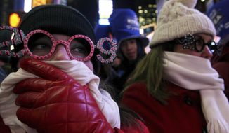 FILE- In this Dec. 31, 2008 file photo, Allison Smith of Jacksonville, Fla, left, tries to keep warm as she and others take part in the New Year&#39;s Eve festivities in New York&#39;s Times Square. Brutal weather has iced plans for scores of events in the Northeast U.S. from New Year’s Eve through New Year’s Day, but not in New York City, where people will start gathering in Times Square up to nine hours before the famous ball drop.  (AP Photo/Tina Fineberg, File)