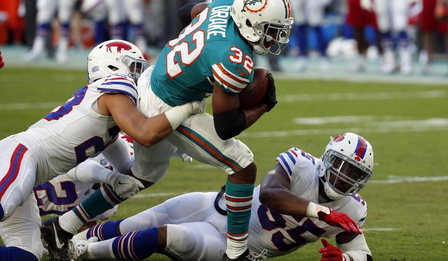 Buffalo Bills strong safety Micah Hyde (23) tackles Miami Dolphins running back Kenyan Drake (32), during the first half of an NFL football game, Sunday, Dec. 31, 2017, in Miami Gardens, Fla. To the right is Buffalo Bills defensive end Jerry Hughes (55). (AP Photo/Wilfredo Lee)