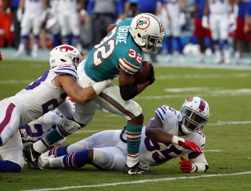 Buffalo Bills strong safety Micah Hyde (23) tackles Miami Dolphins running back Kenyan Drake (32), during the first half of an NFL football game, Sunday, Dec. 31, 2017, in Miami Gardens, Fla. To the right is Buffalo Bills defensive end Jerry Hughes (55). (AP Photo/Wilfredo Lee)